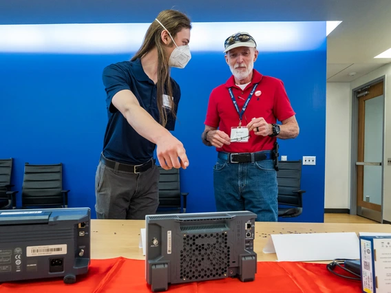 two people talking, one pointing to electrical equipment
