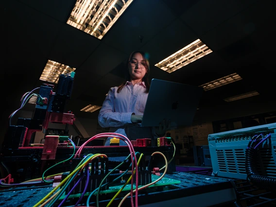 A woman stands near electrical wires.