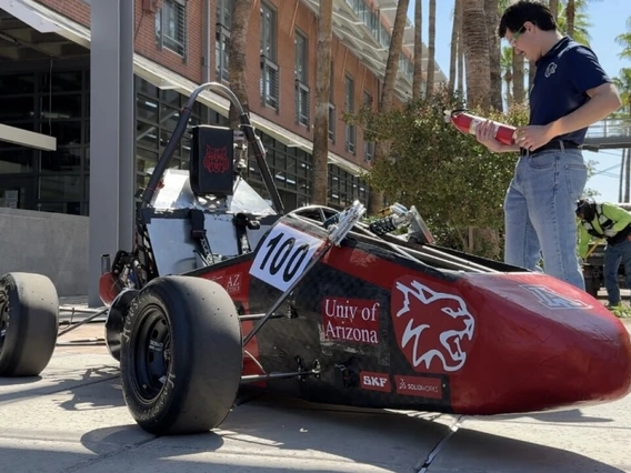 An engineering student stands by the Wildcat Formula Racing club's "WF25" vehicle on the University of Arizona campus.