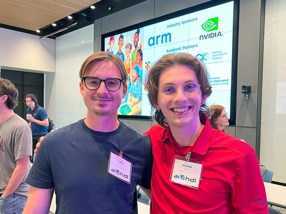 two people, smiling, digital monitor in background