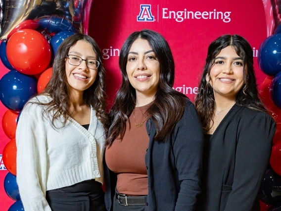 Three people standing in front of Univ of AZ Engineering backdrop with balloons