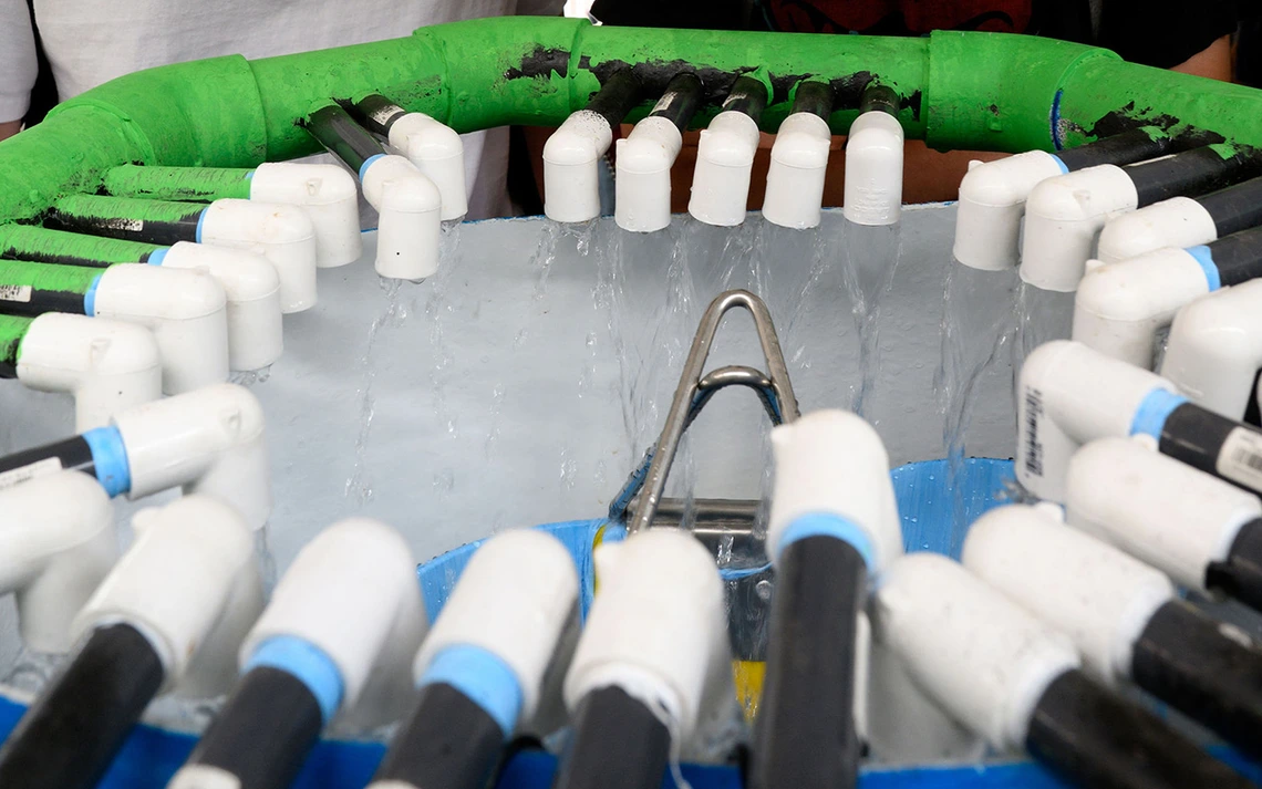 A white tank has a ring of tubes that flow water.