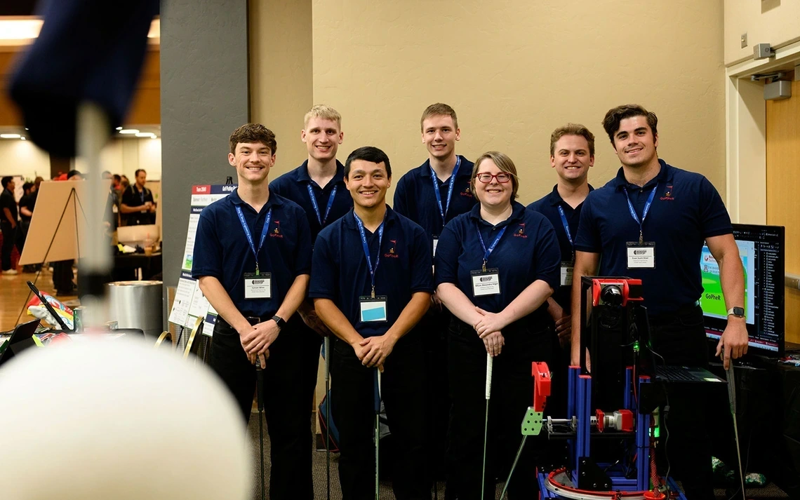 group of students wearing blue polo shirts and lanyards, holding golf clubs