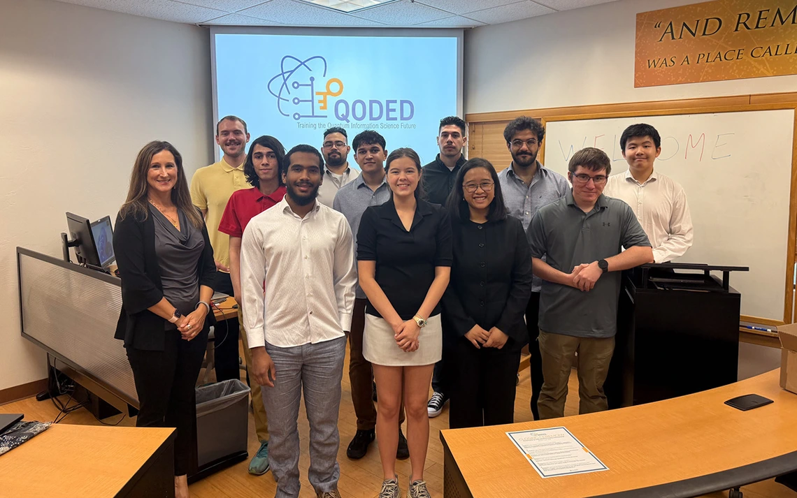 A woman with brown hair poses for a photo with a bunch of students.