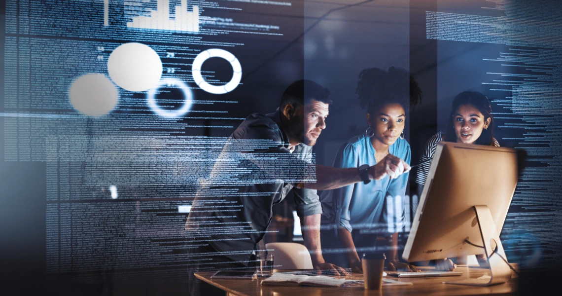 three people gathered around a computer monitor