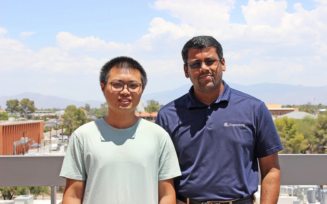 A man with a light blue shirt and another man with a dark blue shirt stand on top of a building.