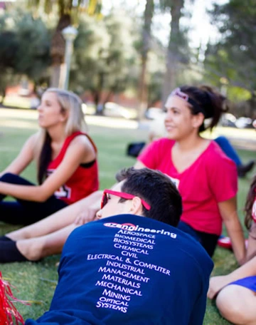 three students on lawn, one student wearing sunglasses