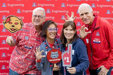 four people, smiling, several holding Univ of AZ SWAG