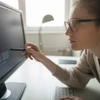Woman examines code on a computer screen.
