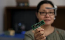 A woman with dark brown hair holding a computer circuit