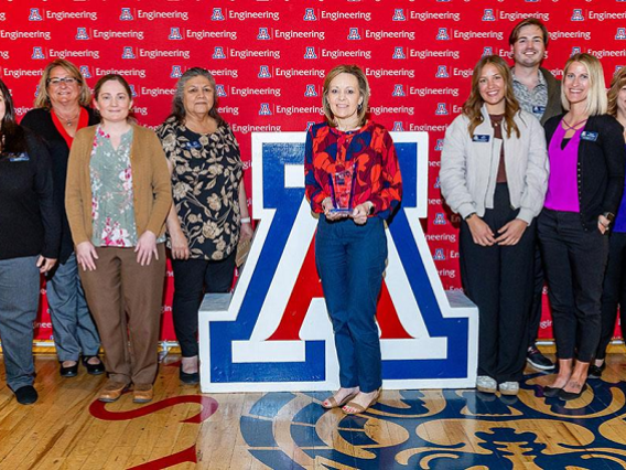 group of people standing by Univ. of Arizona block A. Woman holding award