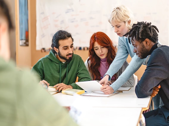 group of students, gathered around a table, reviewing on object