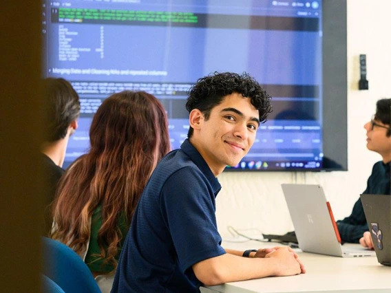 person, smiling, computer screen and students in background