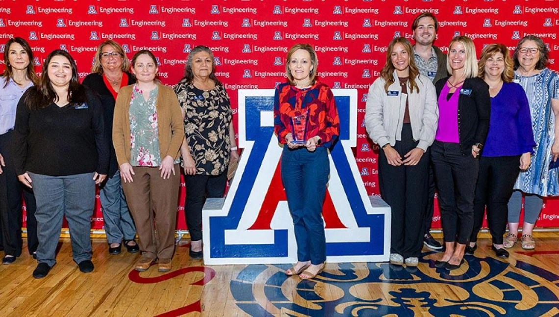 group of people standing by Univ. of Arizona block A. Woman holding award