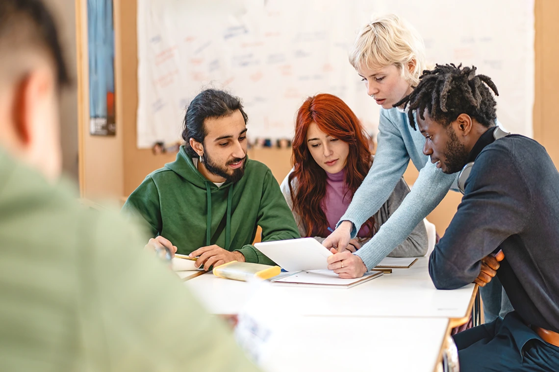 group of students, gathered around a table, reviewing on object