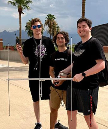 three students, holding wireless communications equipment