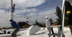 Students stand on a roof wearing hard hats and installing an antenna