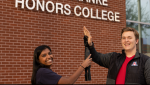 Nisha Rajakrishna and Collin Preszler do a mock high-five with a prosthetic arm