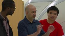 Associate professor Ali Bilgin (center) speaks with two of his grad students in front of an MRI machine.