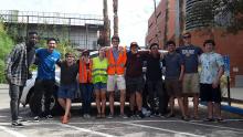 University of Arizona REU students, some in yellow and orange safety vests, stand together in front of the UA CAT vehicle