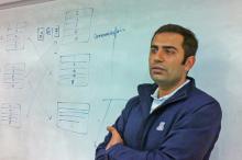 Ravi Tandon stands in front of a whiteboard in a blue UA jacket