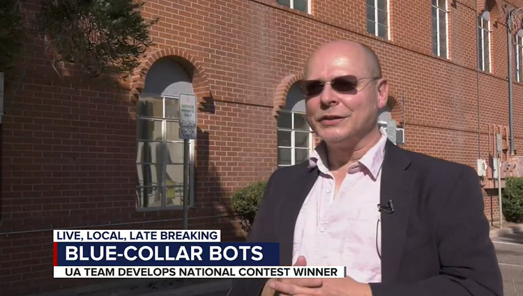 Screencap of Wolfgang Fink speaking on a news segment. Lower third reads "Blue-Collar Bots: UA Team Develops National Contest Winner"